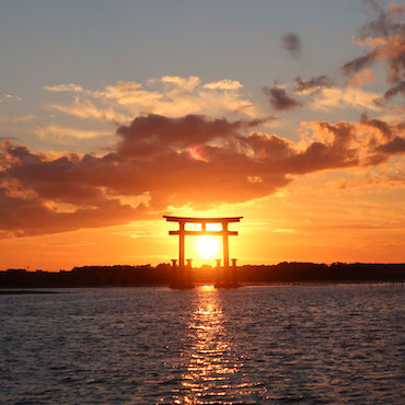 鳥居の中に夕日が沈んでいく様子の画像